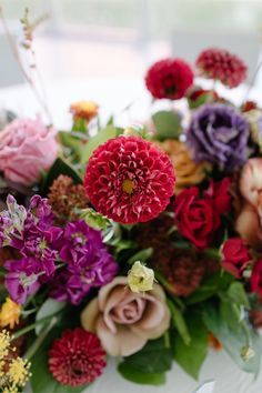 a bunch of flowers sitting on top of a white table covered in leaves and flowers