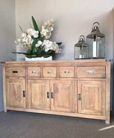 a vase with flowers on top of a wooden cabinet