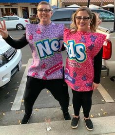 two people standing in front of a car with their hands up and wearing nerds t - shirts