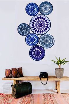 a wooden bench sitting next to a wall with blue plates hanging on it's side