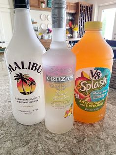 three bottles of liquid sitting on top of a counter next to an orange and white bottle