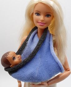 a barbie doll holding a baby wrapped in a blanket