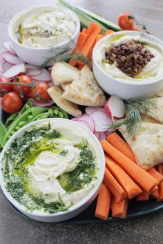 a platter filled with hummus, carrots, celery and pita chips