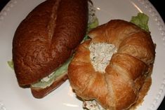 two croissants with chicken salad on them are sitting on a white plate