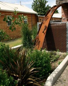 a large metal object sitting in the middle of a garden next to a fenced yard