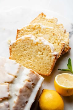 slices of lemon bread with icing on a white plate next to two lemons