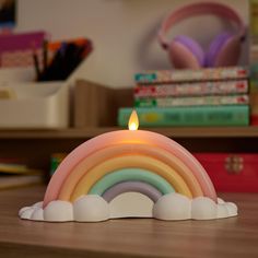 a rainbow shaped candle sitting on top of a wooden table