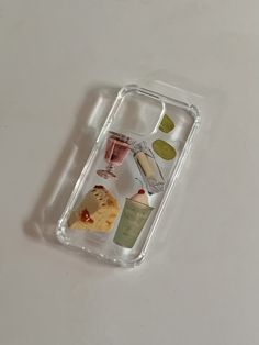 an iphone case with various items in it on a white surface, including wine glasses and cookies