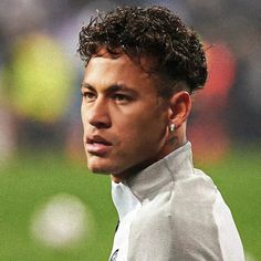 a close up of a soccer player wearing a gray jacket and earrings on his head