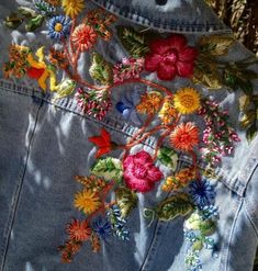 an embroidered jean jacket with flowers and leaves on the back, is seen in close up