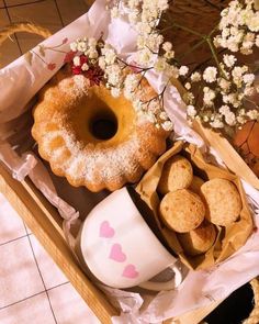 an assortment of pastries in a box on a table next to a cup and saucer