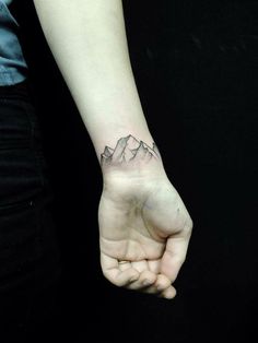 a hand with a mountain tattoo on it