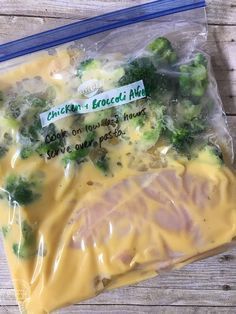 a plastic bag filled with broccoli and cheese on top of a wooden table