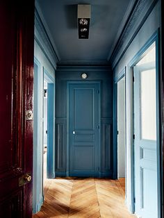 an empty hallway with blue walls and wooden floors