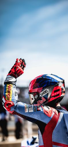 a person wearing a red and blue helmet holding up their hand in the air with other hands