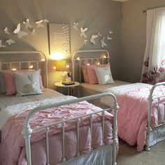 two twin beds with pink comforters and white headboards in a girls'bedroom