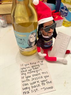 an elf is sitting next to a bottle of wine with a note written on it