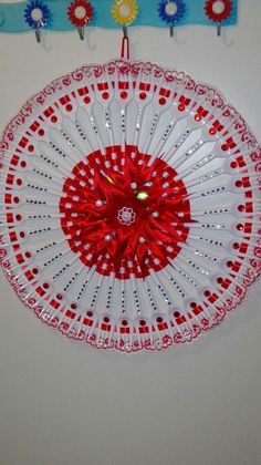 a decorative red and white fan hanging on the wall next to a blue ribbon with flowers