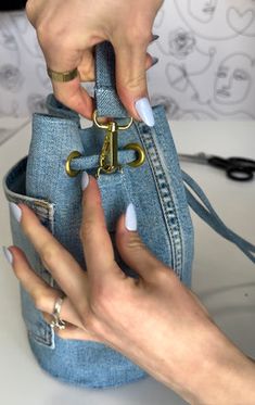 two hands holding onto a blue purse with gold hardwares on the handles and sides