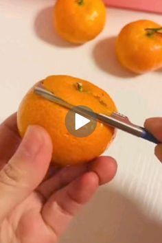 someone is cutting an orange with a pair of scissors on top of it