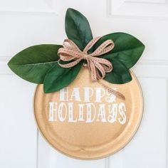 a happy holidays sign is hanging on the front door with green leaves and a bow