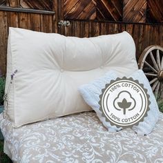 a white pillow sitting on top of a bed next to a wooden fence and wheel