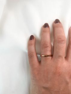 a woman's hand with a gold ring on top of her left hand, resting against a white sheet