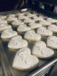 heart shaped cookies with the word love spelled in white frosting on a baking sheet