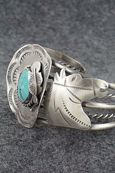 This amazing turquoise and sterling silver bracelet featuring horses and a hat a with feather in the brim was made by Navajo silversmith Tim Yazzie. The back is signed T Yazzie and stamped sterling.Size: 5 5/8" (will fit up to a 6 7/8" wrist)Gap: 1 1/4"Width: 1 5/8"Free shipping on all orders! We ship with USPS and always include tracking. All orders ship within a day of payment.Returns are accepted up to 30 days after you receive your order. Just send us a message. Our shop offers cash back or Western Style Engraved Jewelry For Rodeo, Western Engraved Jewelry For Rodeo, Artisan Silver Jewelry For Rodeo, Adjustable Western Sterling Silver Bracelet For Gift, Handmade Western Sterling Silver Bracelet For Gift, Western Style Silver Jewelry For Shows, Engraved Silver Jewelry For Rodeo, Western Sterling Silver Cuff Bracelet, Western Sterling Silver Bracelets