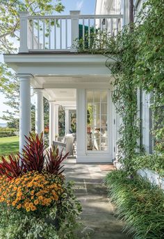 the front porch is surrounded by plants and flowers