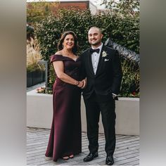 a man in a tuxedo and woman in a gown pose for a photo