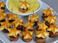 small appetizers are arranged on a plate next to a bowl of dipping sauce