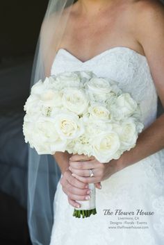 a bride holding a bouquet of white roses