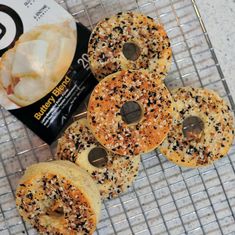 bagels with sprinkles are sitting on a cooling rack next to a packet of ice cream