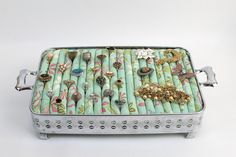 a metal box with many different types of jewelry on it's lid and handles