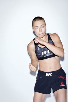 a female fighter posing for the camera with her fist in one hand and looking at the camera