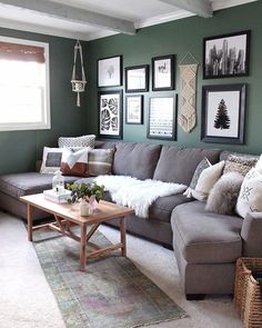 a living room with green walls and pictures on the wall above the sectional couch, coffee table