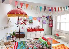 a room with many colorful flags hanging from the ceiling, and a bed in front of a window