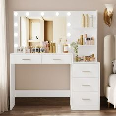 a white vanity with lights on it and a bed in front of the mirror that is next to it