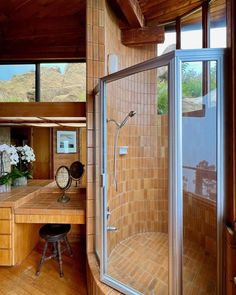 a bathroom with a wooden floor and tiled walls, along with a walk in shower