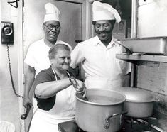 two men and a woman are cooking in a kitchen