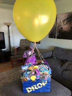 a yellow balloon sitting on top of a blue box filled with candy and candies