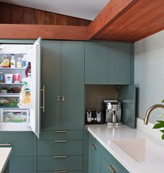 a kitchen with green cabinets and white counter tops, along with a coffee maker on the wall