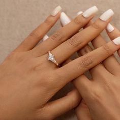 two women's hands with white manicured nails and an engagement ring