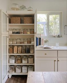 an open pantry with lots of jars and containers on the shelves next to a window