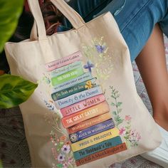 a woman sitting on the floor with a bag full of books and flowers in front of her