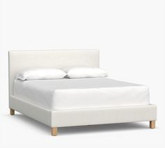 a bed with white linens and pillows on it's headboard is shown