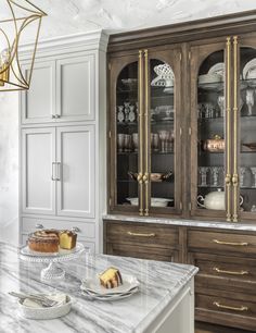 a marble counter top in a kitchen with wooden cabinets and glass front china cabinet doors