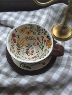 a white and brown bowl sitting on top of a checkered table cloth next to a brass faucet