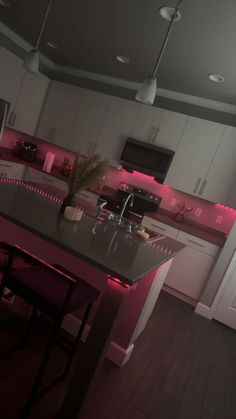 a kitchen with an island and pink lighting